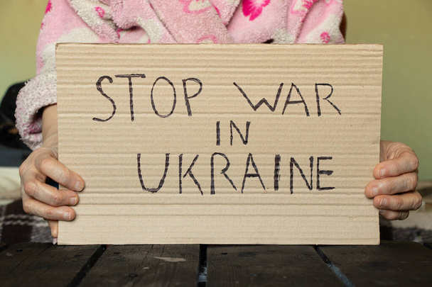Detener la guerra en Ucrania escrito en un cartel que una mujer sostiene en sus manos de su casa en el Dnieper, acción de protesta, ley marcial en Ucrania - Foto, imagen