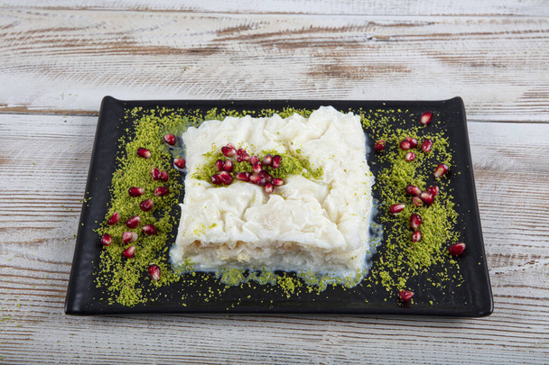 Turecki tradycyjny Ramadan Deser Gullac na stole. Wykonany jest z gulaszu, mleka, wody różanej, orzecha włoskiego, wanilii. Jest ozdobiony granatem i pistacją. Deser z kuchni osmańskiej - Zdjęcie, obraz