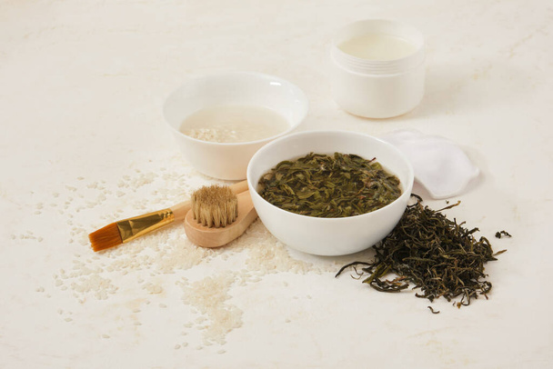 water from rice and tea for skin care in bowls, fermented cosmetics at home, natural ingredients for self-care, brush and brush for applying mask, light background - Foto, Bild