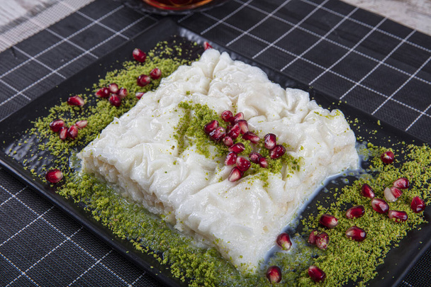 Ramadan tradizionale turco Dessert Gullac sul tavolo. È fatto con gullac, latte, acqua di rose, noce, vaniglia. È decorato con melograno e pistacchio. Dessert dalla cucina ottomana - Foto, immagini