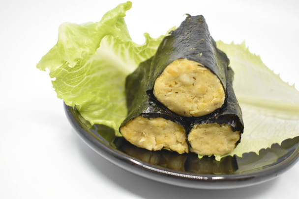 Sushi avec draps nori et houmous de pois chiches avec laitue sur une assiette noire. Fond gris clair. - Photo, image