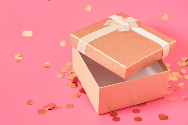 box with a golden lid on a pink background strewn with confetti copy space mock up blank template - Φωτογραφία, εικόνα