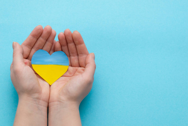 The concept of ending the war in Ukraine. heart in the colors of the flag of Ukraine in female hands - Foto, Bild