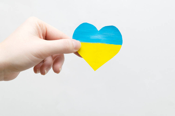 The concept of ending the war in Ukraine. heart in the colors of the flag of Ukraine in female hands - Photo, image