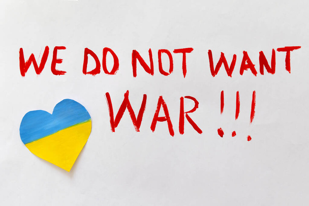 The concept of ending the war in Ukraine. Broken heart in the colors of the flag of Ukraine and Russia in female hands with text we do not want war - Photo, image