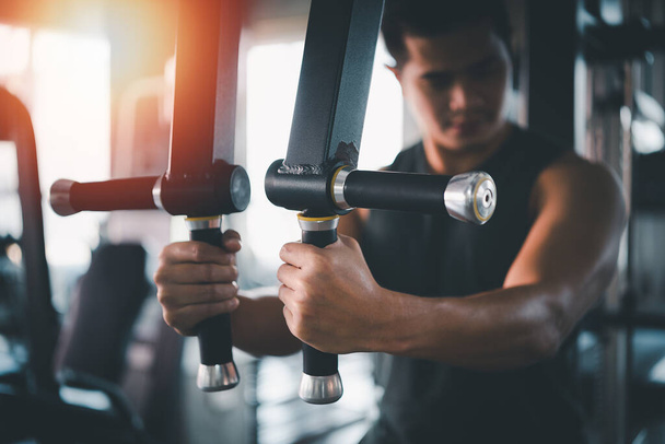 Sportovní muž používající sportovní stroj cvičení v posilovně. Asijské tělo budování pro svalový trénink. Sportovní zdraví tělocvična koncept - Fotografie, Obrázek