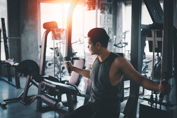 Hombre de deporte usando ejercicio de máquina de deporte en el gimnasio. Culturismo asiático para el entrenamiento muscular. Concepto de gimnasio deportivo - Foto, Imagen