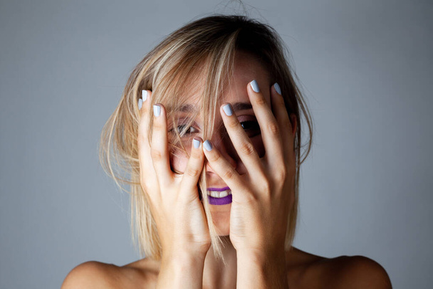 Beautiful blond girl with purple lipstick studio portrait. Hand gestures. - Valokuva, kuva