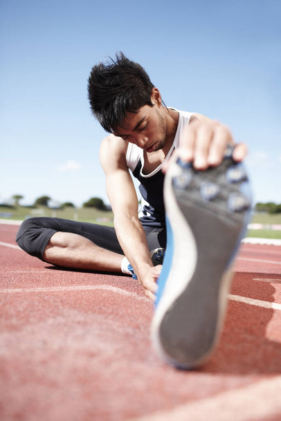 Loosening up... A young athlete focussing on stretching. - Photo, Image