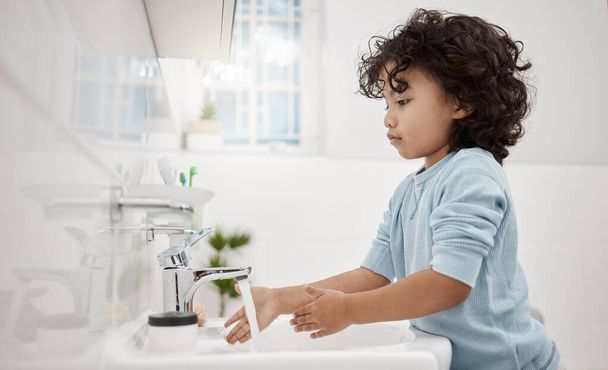 Kinderen moeten hun handen schoon houden. Shot van een schattige kleine jongen wassen zijn handen op een kraan in een badkamer thuis. - Foto, afbeelding