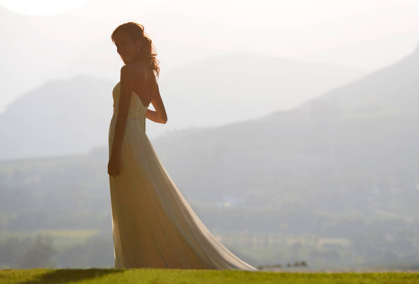 Ihre Schönheit passt zur Landschaft. Eine schöne Braut mit einer malerischen Aussicht im Hintergrund. - Foto, Bild