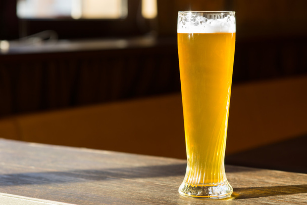 zonovergoten glas bier op tafel - Foto, afbeelding