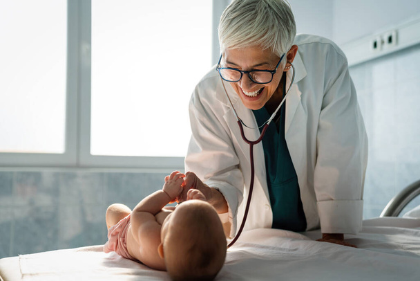 Happy pediatrician doctor examines baby. Healthcare, people, examination concept - Photo, image