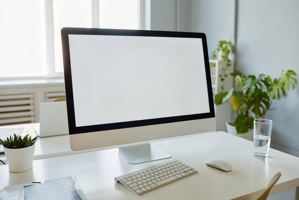 Minimal background image of office workplace with blank white computer screen on desk, copy space - Fotoğraf, Görsel