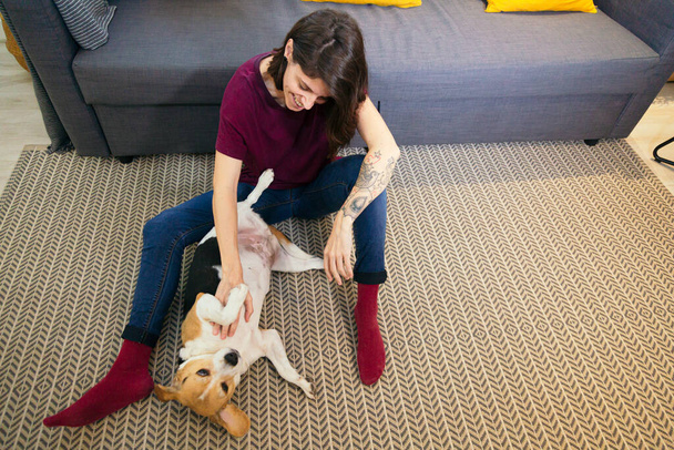 woman scratching her dogs belly on the floor - Photo, Image