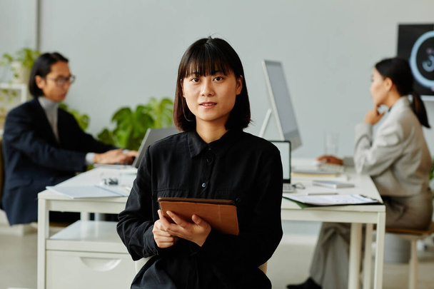 Retrato de vista frontal de la joven empresaria asiática mirando a la cámara mientras sostiene la tableta digital en la oficina - Foto, imagen