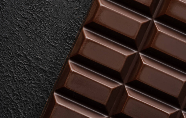 Close-up of broken pieces of chocolate on a dark stone background. - Foto, Bild