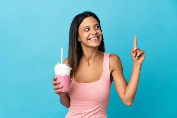 Young woman with strawberry milkshake pointing up a great idea - Photo, Image