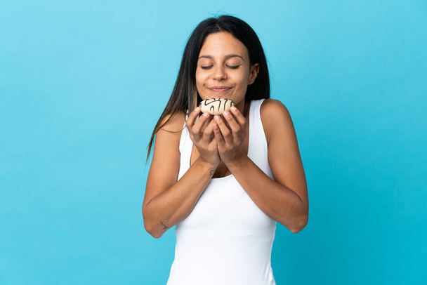 Caucasian girl isolated on blue background holding a donut - Foto, immagini