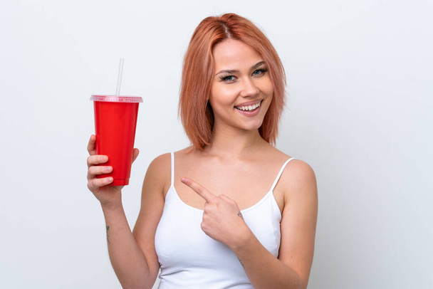 Молода російська жінка, яка тримає безалкогольний напій ізольованим на білому фоні і вказує його - Фото, зображення
