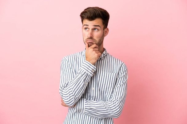 Young caucasian handsome man isolated on pink background having doubts and thinking - Photo, Image
