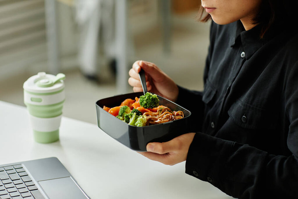 close-up van jonge vrouw genieten van gezonde lunch met groenten in pauze in kantoor, kopiëren ruimte - Foto, afbeelding