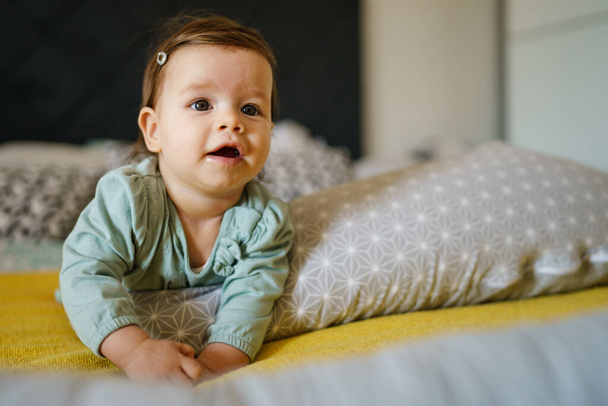 Vista frontal en el pequeño bebé caucásico feliz acostado en la cama en casa en el espacio de copia del día - Foto, Imagen