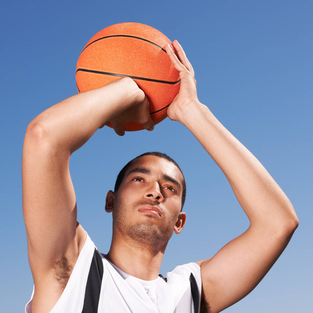 Busco el cielo. Un joven jugador de baloncesto preparando un tiro. - Foto, Imagen