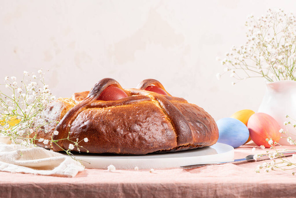 Португальский традиционный пасхальный торт. Фолар с яйцами на пасхальном столе. Цветы и разноцветные расписные яйца - Фото, изображение
