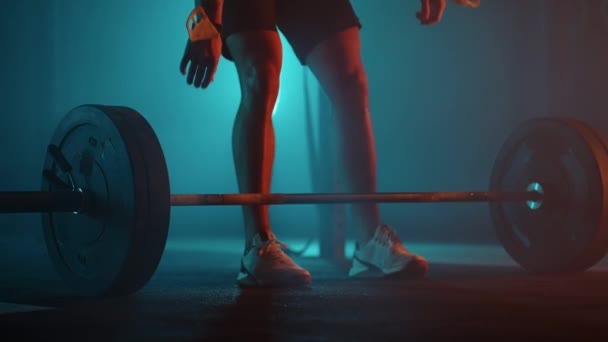 sterke man nadert lange halter in donker dramatische sportschool en tillen gewicht, benen van sporter - Video