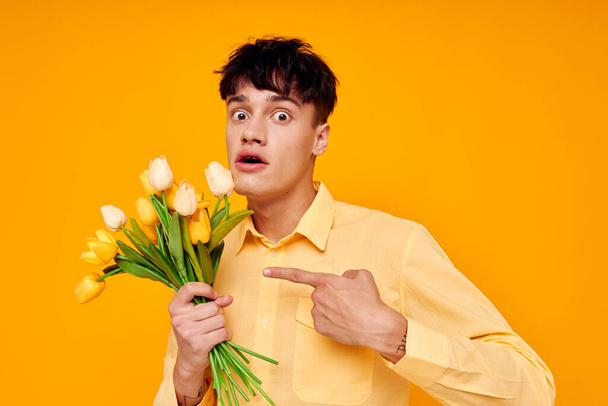 handsome guy in yellow glasses with a bouquet of flowers yellow background unaltered - Foto, imagen