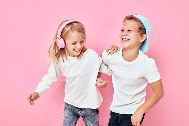 menina com fones de ouvido ao lado de menino dança entretenimento cor de rosa fundo - Foto, Imagem