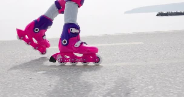 Niña montando patines. Rodando cerca de la costa del mar, 4k video en cámara lenta - Imágenes, Vídeo
