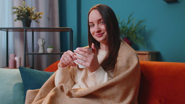 Retrato de mulher adulta jovem sorridente em suéter branco quente beber caneca bebida quente relaxante em casa - Foto, Imagem