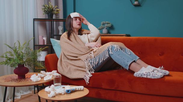 Retrato de mujer joven que sufre de frío o alergia en cuadros acostada en el sofá en la sala de estar en casa - Foto, imagen