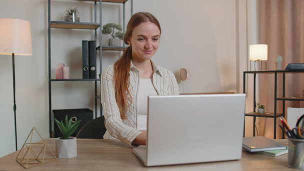 Kaukasische jonge vrouw zitten aan tafel openen laptop pc starten werk online in kamer op kantoor - Foto, afbeelding