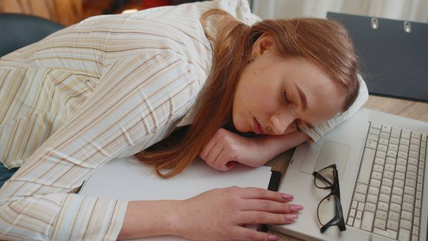 Mujer cansada en la oficina en casa quedarse dormido en la mesa con ordenador portátil, hojas arrugadas de papel - Foto, Imagen