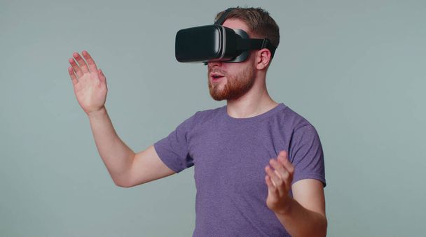 Man met behulp van virtual reality futuristische technologie VR-headset helm om te spelen simulatie 3D video game - Foto, afbeelding