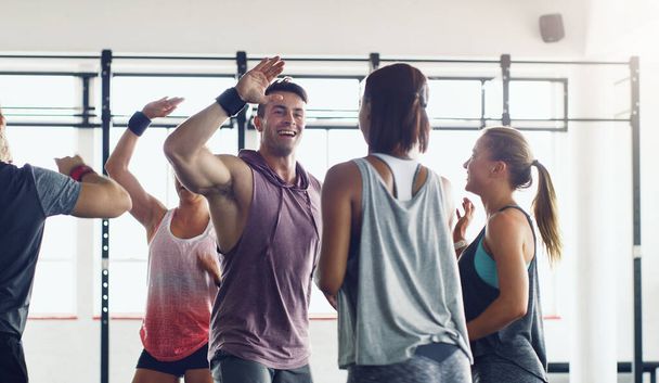 Strong people inspire other people to be strong. Shot of a group of young people motivating each other with a high five in a gym. - Photo, Image