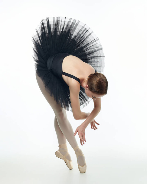 atrakcyjna baletnica stoi na opuszkach palców. sesja zdjęciowa w studio na białym tle. - Zdjęcie, obraz