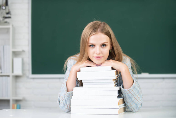Portrait of cute attractive young woman student in university or high school college. Close up portrait of happy attractive young woman student with books on blackboard in classroom. - Φωτογραφία, εικόνα