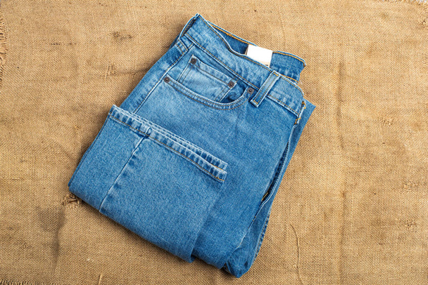 blue classic jeans close-up lie on the background of an old burlap. View from above. - Foto, Imagem