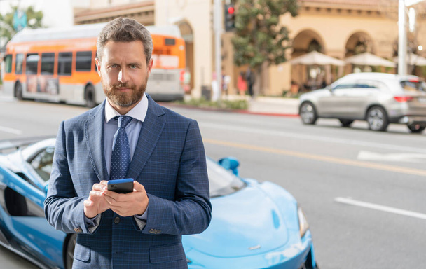 homem de negócios mensagens no telefone ao lado de carro de luxo - Foto, Imagem