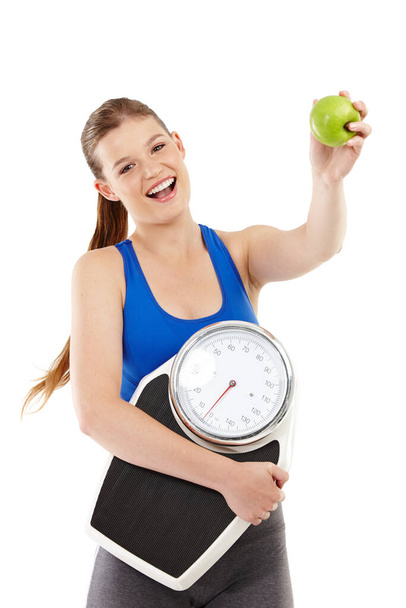 Advocating a healthy lifestyle. A pretty teenager holding an apple in her hand while carrying a scale. - Photo, Image
