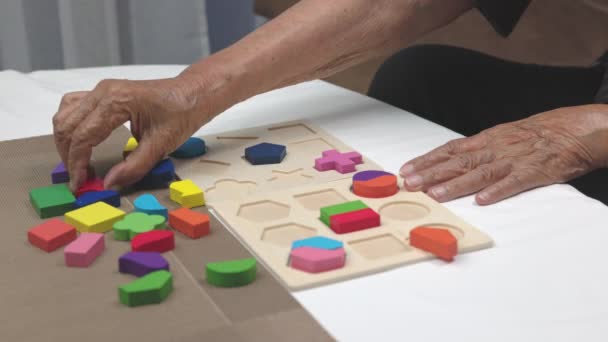 Huoltaja ja vanhempi nainen pelaa puinen muoto palapelit peli dementian ehkäisyyn. - Materiaali, video