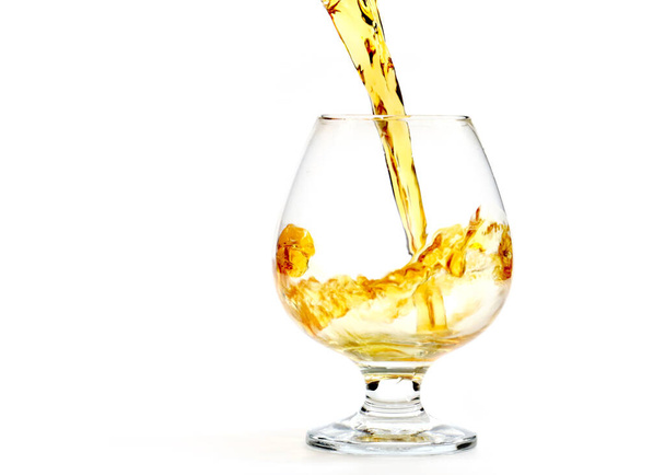 a strong alcoholic drink is poured into a glass - Photo, Image