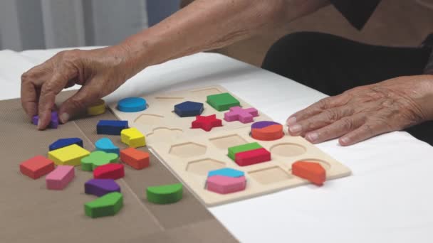 Cuidador y mujer mayor jugando rompecabezas de madera juego para la prevención de la demencia. - Imágenes, Vídeo