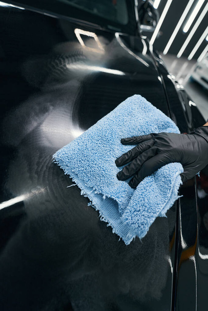 Gloved hand wiping exterior of automobile with cloth - Fotó, kép