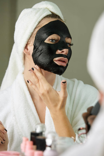 Mulher aplicando máscara de folha preta - Foto, Imagem