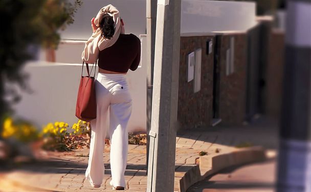 Γυναίκα με λευκό παντελόνι που βγάζει την μπλούζα της στο δρόμο - Φωτογραφία, εικόνα
